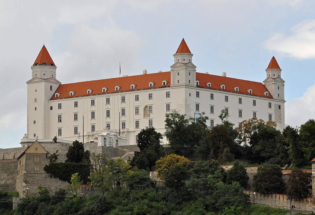 Het witte Bratislava kasteel op de rots boven de Donau met de Old Town en de SNP-brug op de achtergrond