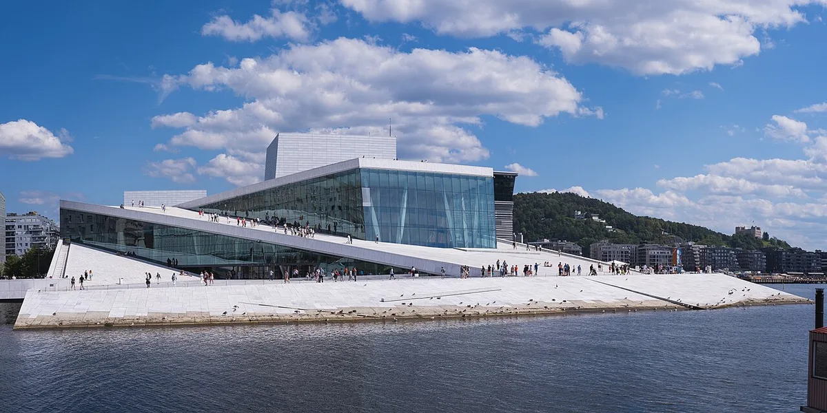 Het witte marmeren operagebouw van Oslo aan de Oslofjord met mensen die erop wandelen